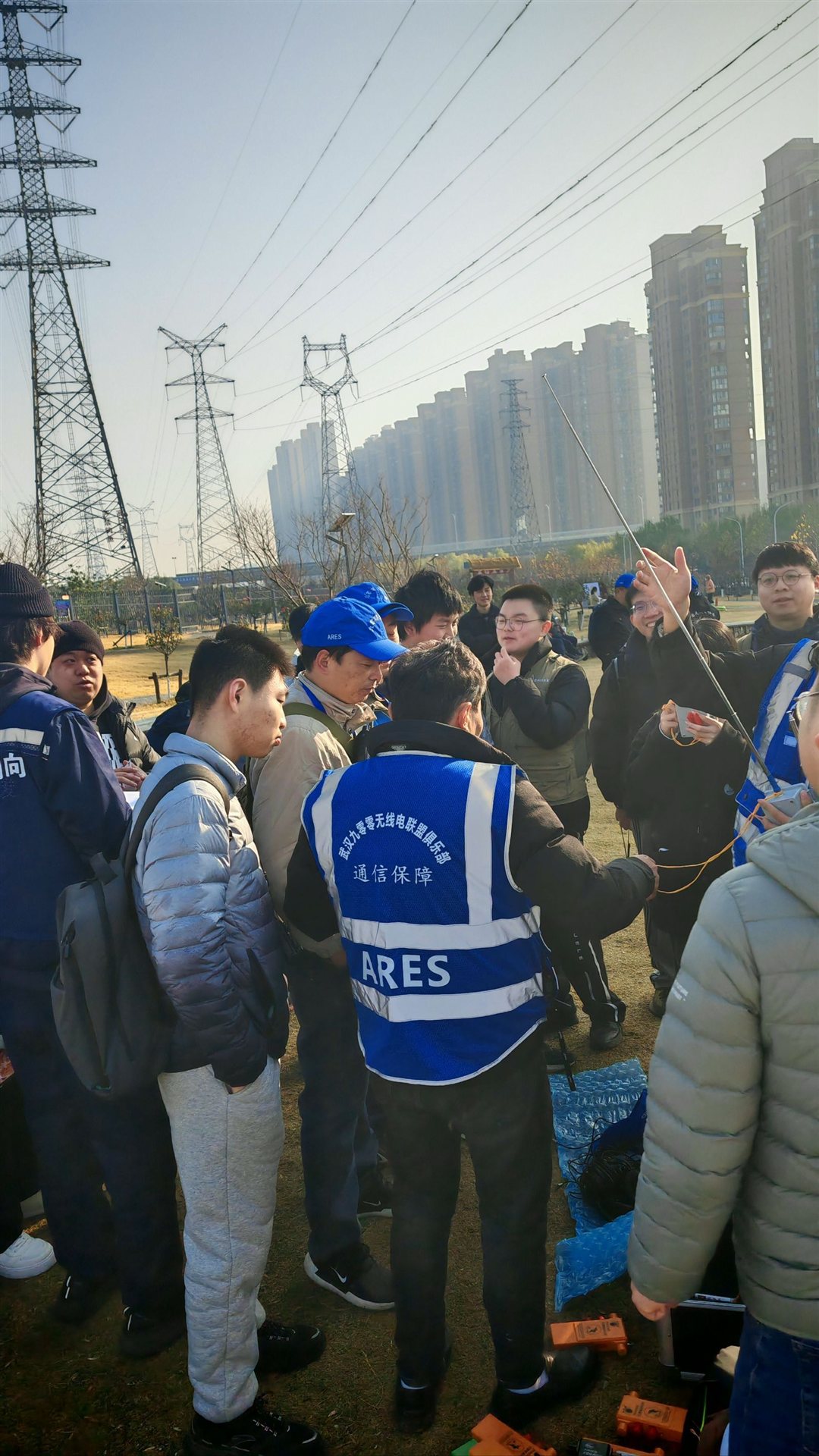 ARES 团队在高压线塔下围圈讨论通信部署